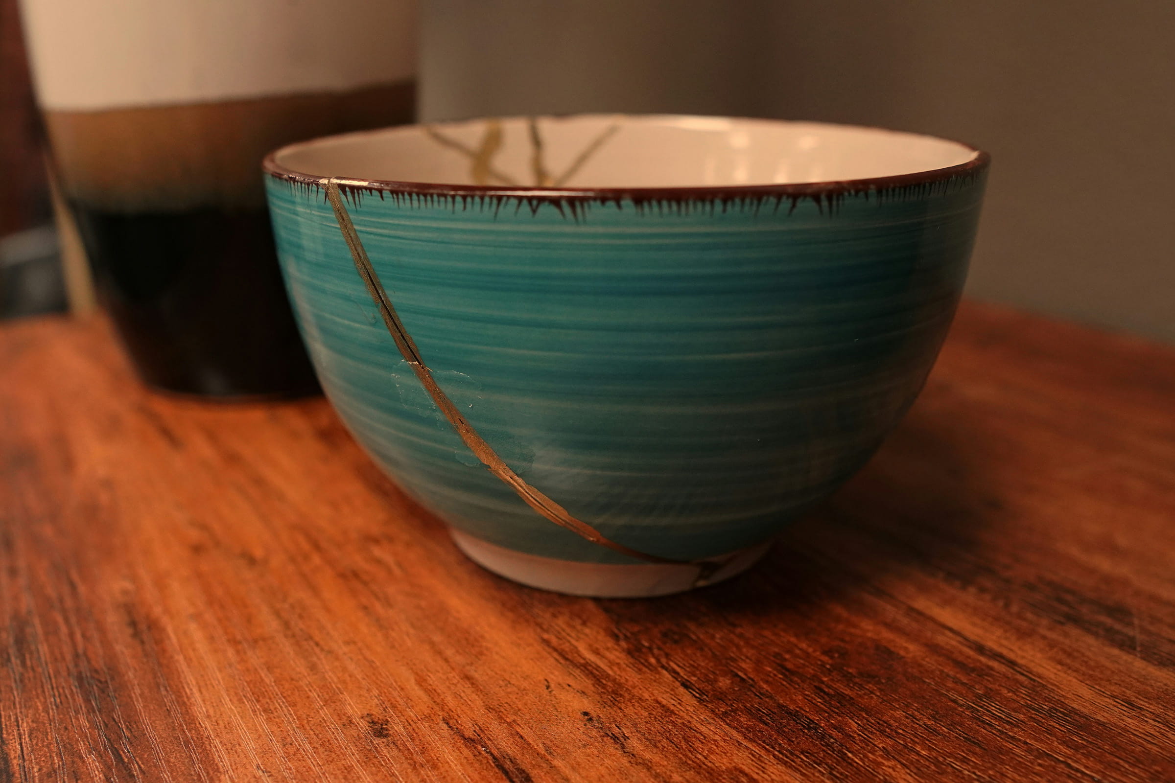 Naprawiona techniką Kintsugi ceramiczna czarka na naturalnym drewnianym stole